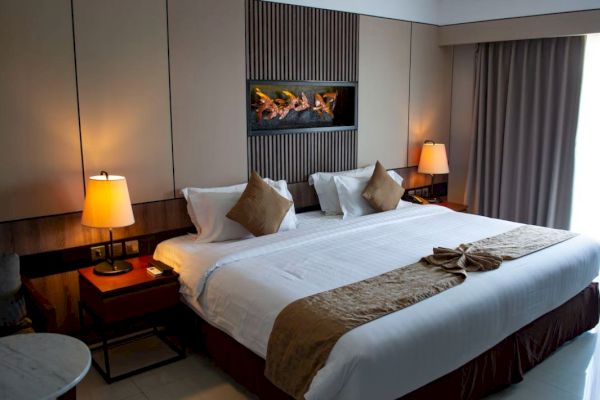 A well-decorated hotel room with a large bed, two lamps, and a window with curtains, creating a cozy atmosphere.