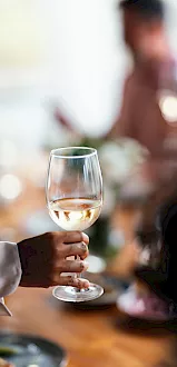 Two people clink champagne flutes outdoors, toasting a special moment with sparkling drinks in the sunshine.