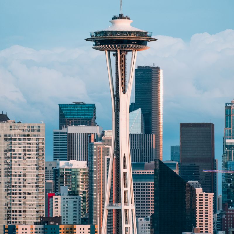 The image shows the Space Needle with surrounding city buildings and a partly cloudy sky.