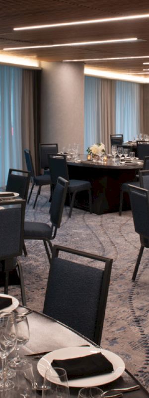 A beautifully set dining room with round tables, elegant place settings, and chairs, ready for an event.